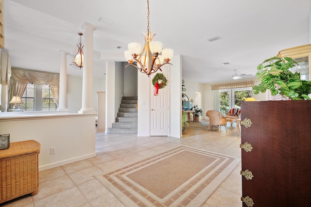 foyer entrance with ornate columns, light tile patterned floors, and a notable chandelier