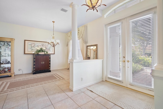 foyer entrance with light tile patterned floors, decorative columns, french doors, and a notable chandelier