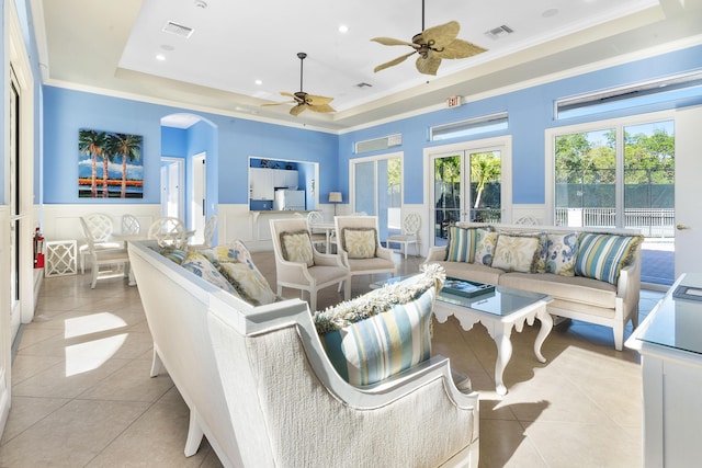 tiled living room with french doors, a tray ceiling, ceiling fan, and ornamental molding