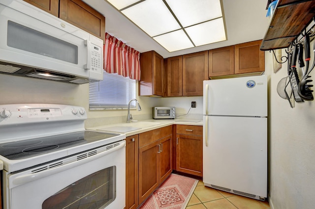 kitchen featuring light tile patterned flooring, white appliances, and sink