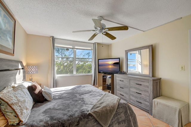 bedroom with ceiling fan, light tile patterned floors, and a textured ceiling