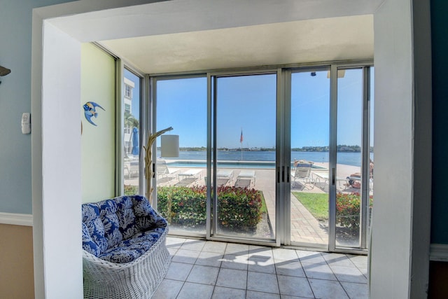 interior space with light tile patterned floors, a wall of windows, a water view, and a wealth of natural light