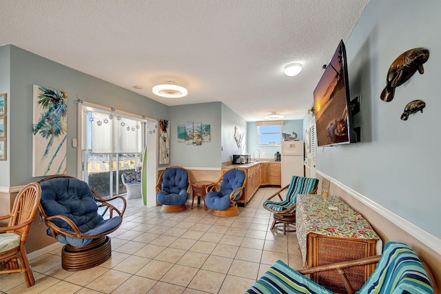 living room featuring sink, light tile patterned floors, and a textured ceiling