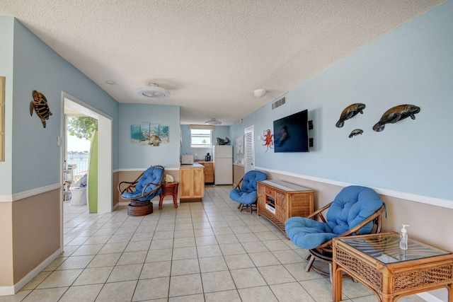 living area with light tile patterned flooring and a textured ceiling