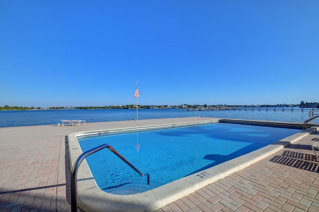 view of swimming pool with a water view and a patio area