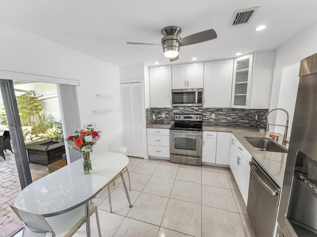 kitchen featuring white cabinets, sink, ceiling fan, appliances with stainless steel finishes, and tasteful backsplash