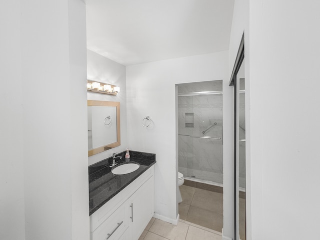 bathroom featuring tile patterned floors, toilet, vanity, and walk in shower