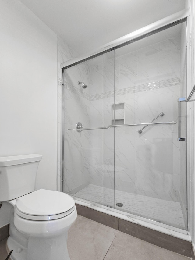 bathroom with tile patterned floors, toilet, and an enclosed shower