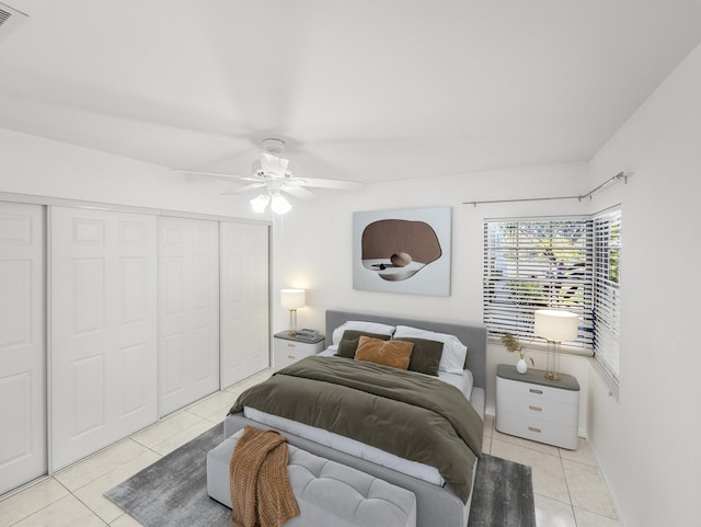 tiled bedroom with ceiling fan and a closet