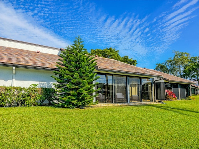 rear view of house featuring a sunroom and a yard