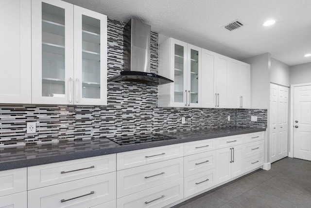 kitchen with white cabinets, wall chimney range hood, backsplash, and black electric cooktop