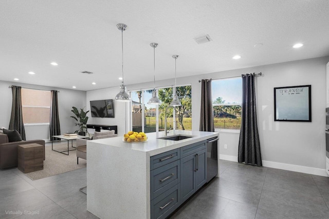 kitchen featuring sink, dishwasher, a textured ceiling, decorative light fixtures, and a center island with sink