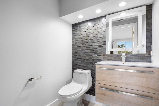 bathroom featuring vanity, toilet, decorative backsplash, and tile walls