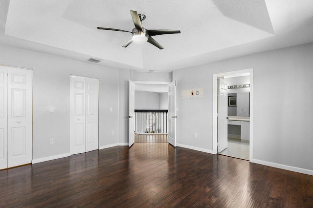 interior space featuring ceiling fan, ensuite bathroom, a textured ceiling, and dark wood-type flooring