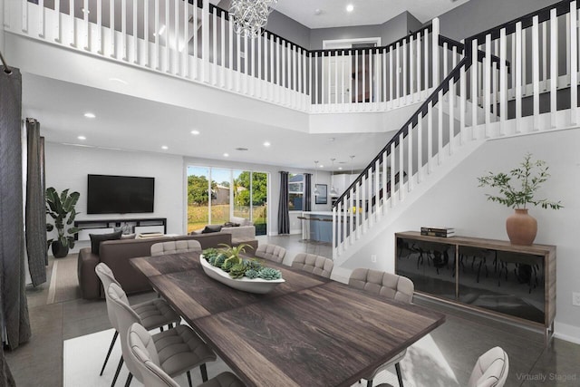 dining area with a towering ceiling and an inviting chandelier