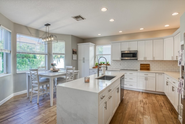 kitchen featuring pendant lighting, stainless steel appliances, light hardwood / wood-style floors, and sink