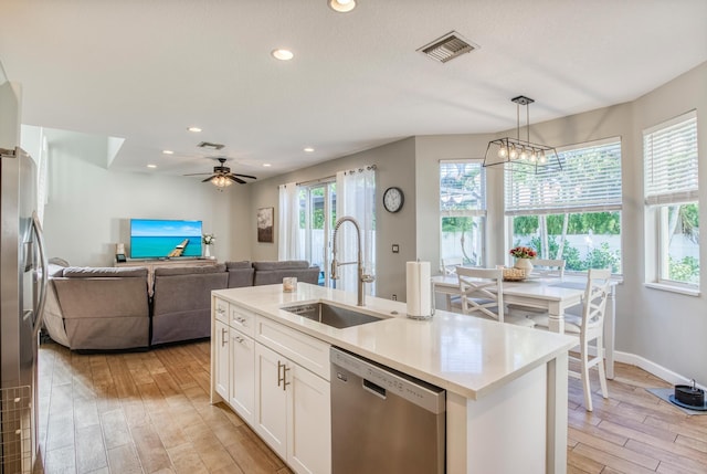 kitchen featuring a wealth of natural light, stainless steel appliances, hanging light fixtures, and an island with sink