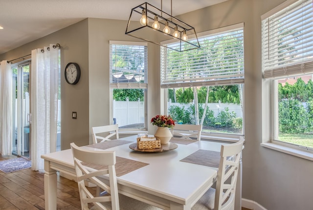 dining room featuring wood-type flooring, a healthy amount of sunlight, and a notable chandelier