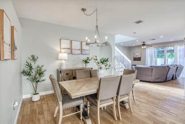 dining room with ceiling fan with notable chandelier and light wood-type flooring