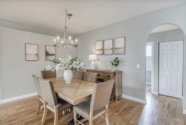 9128 Dupont Pl, Wellington, FL 33414 - dining space featuring arched walkways, light wood-style flooring, a chandelier, and baseboards