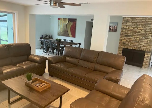 tiled living room featuring a fireplace and ceiling fan