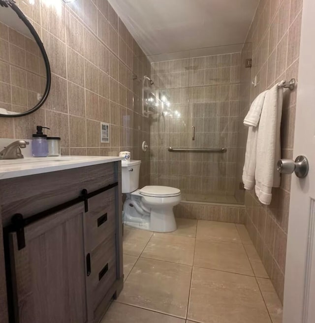 bathroom with vanity, a shower, tile patterned floors, toilet, and tile walls