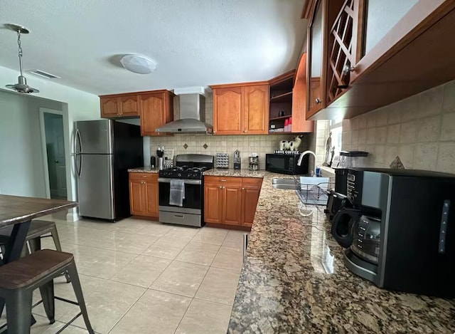 kitchen with light stone counters, stainless steel appliances, sink, wall chimney range hood, and light tile patterned flooring