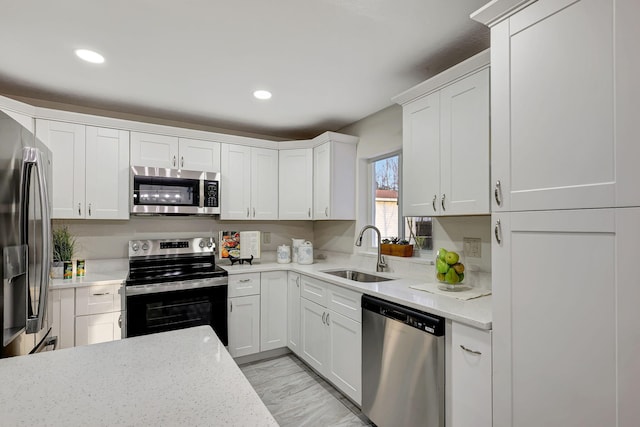 kitchen featuring appliances with stainless steel finishes, light stone counters, white cabinetry, and sink