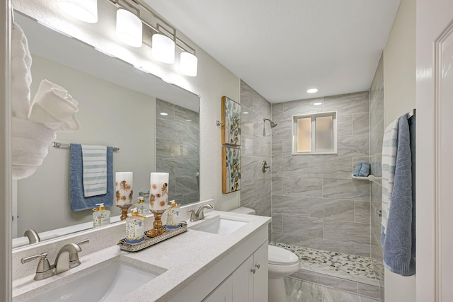 bathroom featuring a tile shower, vanity, and toilet