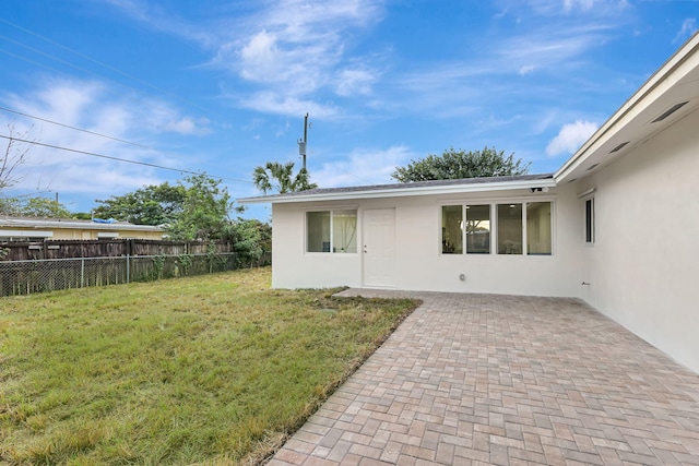 back of house with a lawn and a patio area