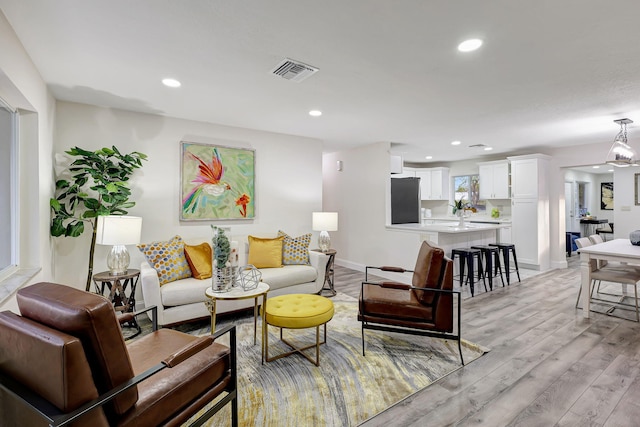 living room with an inviting chandelier and light hardwood / wood-style flooring