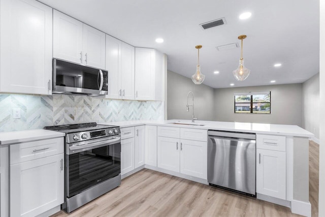 kitchen with white cabinetry, sink, kitchen peninsula, pendant lighting, and appliances with stainless steel finishes