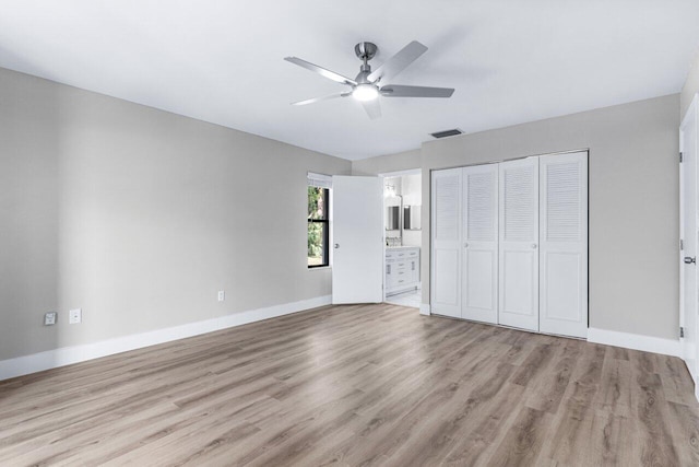 unfurnished bedroom featuring light wood-type flooring, a closet, ensuite bath, and ceiling fan