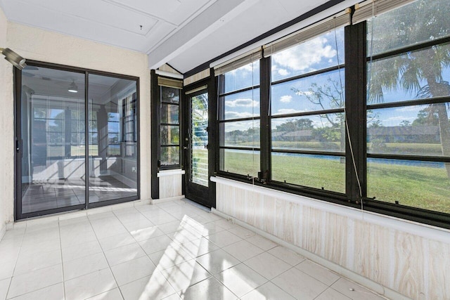 unfurnished sunroom with beam ceiling and a water view