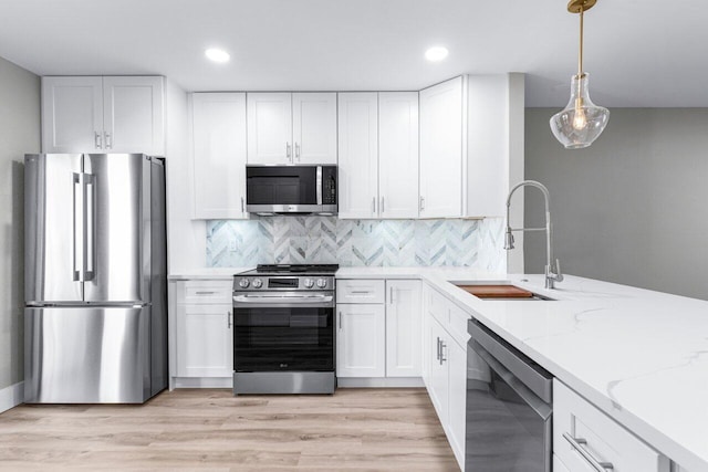 kitchen with white cabinetry, sink, decorative light fixtures, and appliances with stainless steel finishes