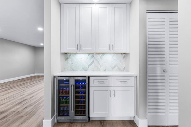 bar with white cabinets, tasteful backsplash, wine cooler, and light hardwood / wood-style flooring