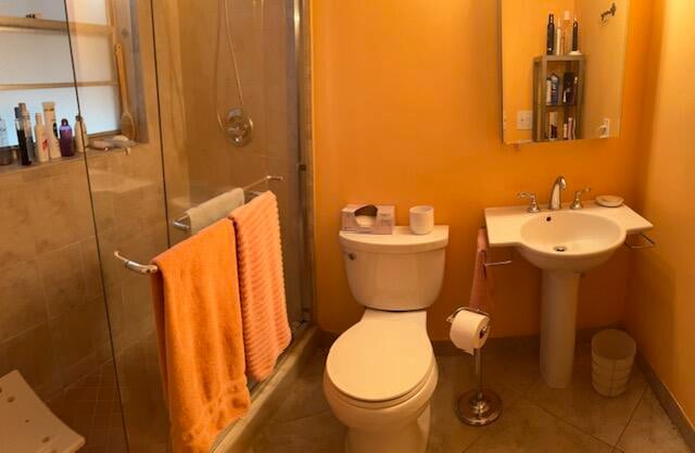 bathroom featuring tile patterned flooring, toilet, and a shower with door