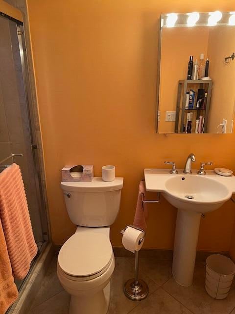 bathroom with toilet, tile patterned floors, and a shower with shower door