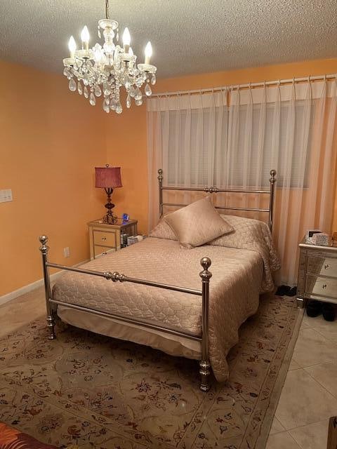 bedroom featuring light tile patterned floors, a textured ceiling, and an inviting chandelier