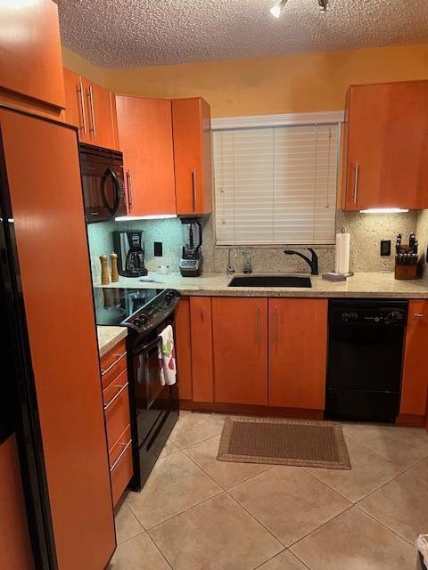 kitchen featuring sink, a textured ceiling, decorative backsplash, light tile patterned flooring, and black appliances