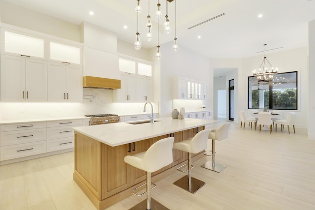 kitchen with white cabinetry, a large island, decorative light fixtures, and sink