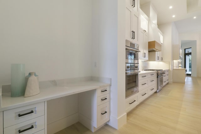 kitchen featuring white cabinetry, light stone counters, light hardwood / wood-style floors, and appliances with stainless steel finishes