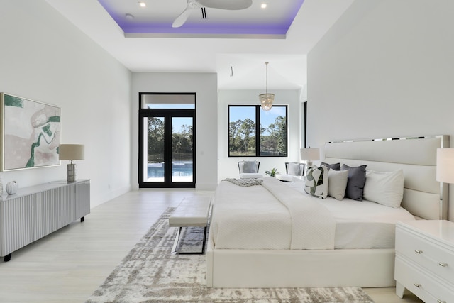 bedroom featuring french doors, ceiling fan, a tray ceiling, and light hardwood / wood-style floors