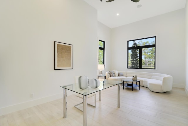 living room featuring a towering ceiling, light hardwood / wood-style flooring, and ceiling fan