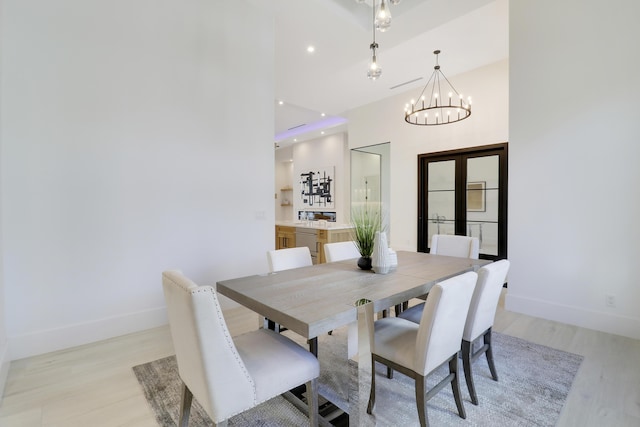 dining space with light hardwood / wood-style flooring and a notable chandelier