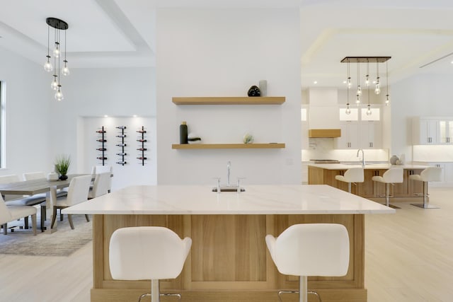 kitchen featuring a large island, light stone counters, decorative light fixtures, and white cabinetry