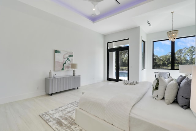 bedroom with french doors, a chandelier, multiple windows, and light wood-type flooring