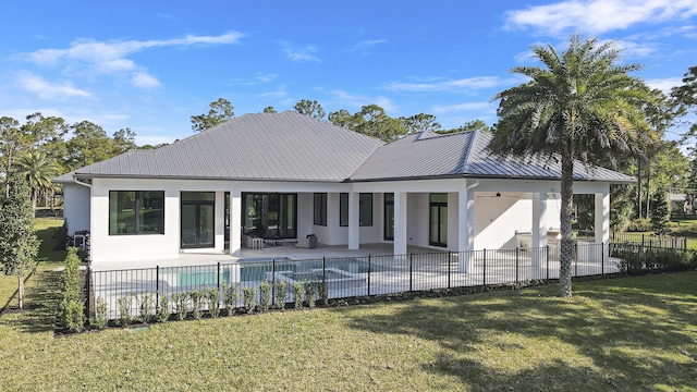 rear view of property featuring a fenced in pool, a lawn, and a patio