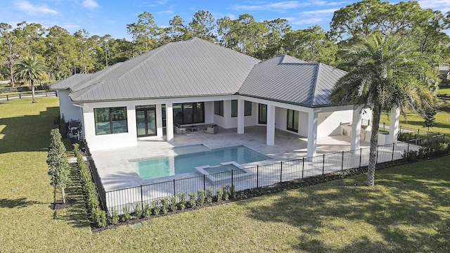 back of house featuring a swimming pool with hot tub, a patio, and a lawn