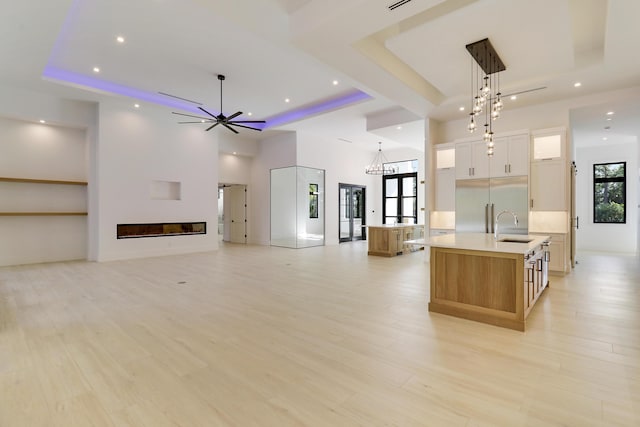 kitchen with white cabinetry, a tray ceiling, a spacious island, and sink